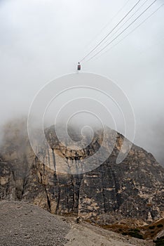 Cloudy fogy sky mountain peak covered in mist in the morning. Teleferic cable car . Dolomite alps photo