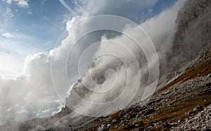 Cloudy fogy sky mountain peaks covered in mist in the morning. Dolomite rocky mountains Italy