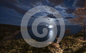 Cloudy full moon and pretty girl in a cliff border seascape