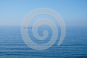 Cloudy horizon and Fog over the sea waves, natural background, red cargo ship on the horizon