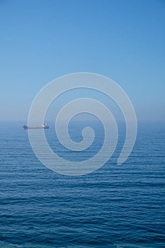 Cloudy horizon and Fog over the sea waves, natural background, red cargo ship on the horizon