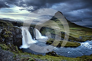 Cloudy overcast day of the Kirkjufellsfoss Waterfall with Kirkjufell mountain in the background in Iceland.