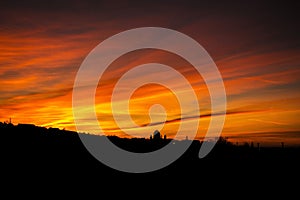 Cloudy rose blue sunset over dark silhouettes of city buildings,