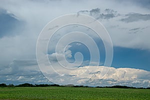 Cloudy skies above canola fields, Saskatchewan, Canada.