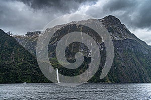 Cloudy skies over a waterfall in Milford Sound, Fiordland National Park on New Zealand\'s South Island