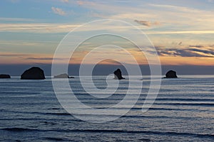 Cloudy skies and sunset over Oregon Coast Pacific ocean rocky outcrops