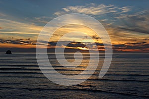 Cloudy skies and sunset over Oregon Coast Pacific ocean rocky outcrops photo