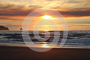 Cloudy skies and sunset over Oregon Coast Pacific ocean rocky outcrops photo