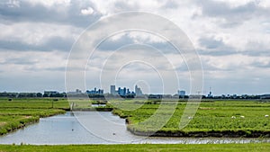 Cloudy sky above the skyline of Rotterdam city seen from a polder