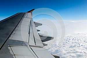 cloudy sky and airplane wing as seen through window of an aircraft.