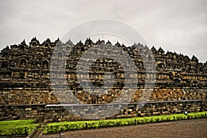 cloudy sky and borobudur temple surrounded by fresh green grass at magelang, indonesia