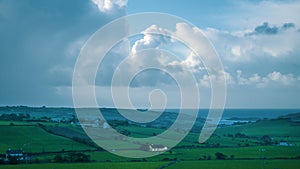 Cloudy sky over the green rolling fields of southern Ireland. Landscape of the southern coast of Ireland with blue sky and clouds