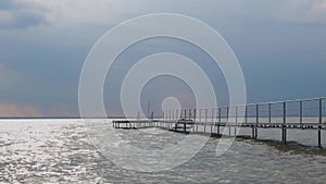 Cloudy sky over the lake Balaton in Hungary. Metal pier in the water