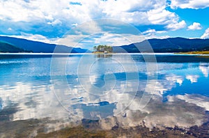 Cloudy sky reflecting in Dospat lake Rhodopes Bulgaria