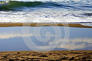 Cloudy sky reflection into water over the beach