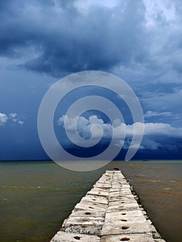 cloudy sky on the sea where there is a bridge leading to the sea, dark clouds,