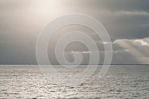 Cloudy sky with sun rays in the open sea