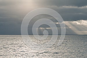 Cloudy sky with sun rays in the open sea