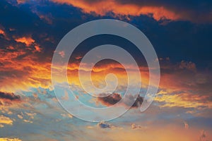 Cloudy sky at sunset. Dark blue and yellow natural background or wallpaper. The rays of the setting sun effectively illuminate the