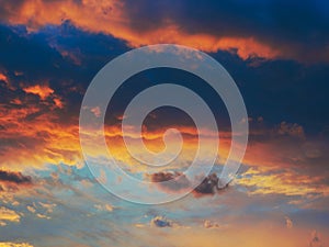 Cloudy sky at sunset. Dark blue and yellow natural background or wallpaper. The rays of the setting sun effectively illuminate the