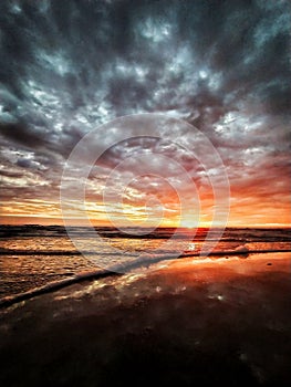 Cloudy sky sunset. Dark clouds. Sea waves. Wet sand.