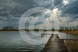Cloudy stormy sky over a lake with a pier