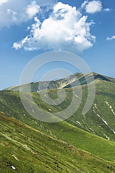 Cloudy summer sky under amazing green mountain chain with rocks