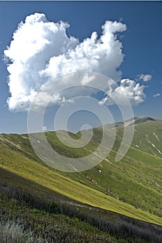 Cloudy summer sky under amazing green mountain chain with rocks