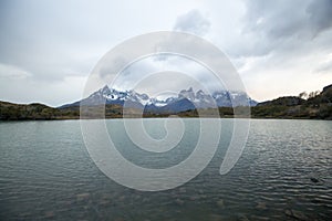 Cloudy sunrise over the Torres del Paine mountains that overlook the waters of a lake, Torres del Paine National Park, Chile