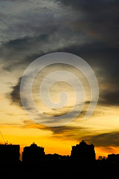 Cloudy sunset over dark silhouettes of city buildings