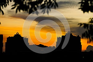 Cloudy sunset over dark silhouettes of city buildings