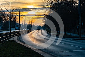 Cloudy sunset over two-lane road with tram rails between