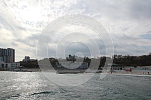 Cloudy weather. Golden sand, waves and foam. Cloudy day on the sandy beach. Panoramic view of beautiful sandy beach