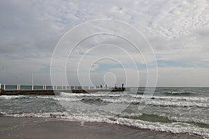 Cloudy weather. Golden sand, waves and foam. Cloudy day on the sandy beach. Panoramic view of beautiful sandy beach