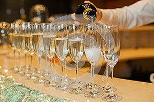 Clous up sparkling champagne bottle filling goblets with wine.