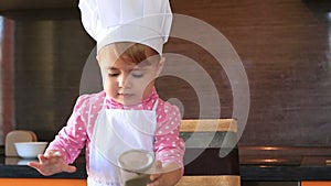 Clouse-up portrait small child in chef suit helps her mother cook in the kitchen