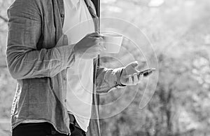 Clouseup of young man using mobile and drinking coffe