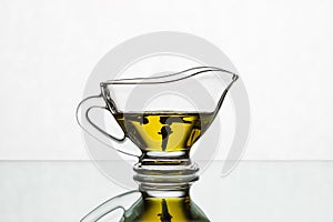 Clove oil in a glass sauceboat on a white background. Spice cloves in a gravy boat