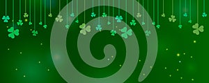 Clover shamrock leaves hung on strings on dark green background. Abstract St. Patrick`s day border horizontal panorama background