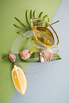Cloves of garlic, slices of lemon and olive oil on blue-green te