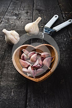 Cloves of garlic on a wooden black table. Fresh garlic bulb with iron garlic press. Vintage background. Farmer. Medicine and healt