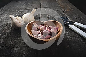 Cloves of garlic on a wooden black table. Fresh garlic bulb with iron garlic press. Vintage background. Farmer. Medicine and healt