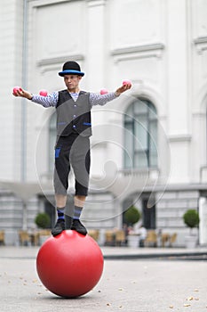 The clown and balancer juggles with pink balls