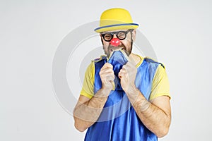 A clown in a bright blue and yellow suit bites his tie from fright