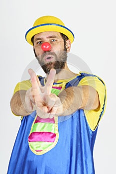 A clown in a bright blue and yellow suit shows a slingshot with his hands - aims