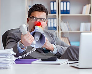 The clown businessman angry in the office with a megaphone