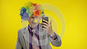 Clown businessman entrepreneur in wig using app on smartphone for online work