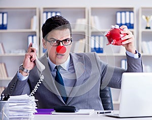 Clown businessman with piggy bank doing accounting