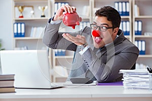 The clown businessman with piggy bank doing accounting