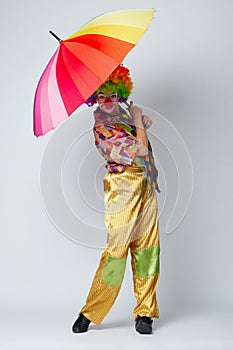 Clown with colorful umbrella on white